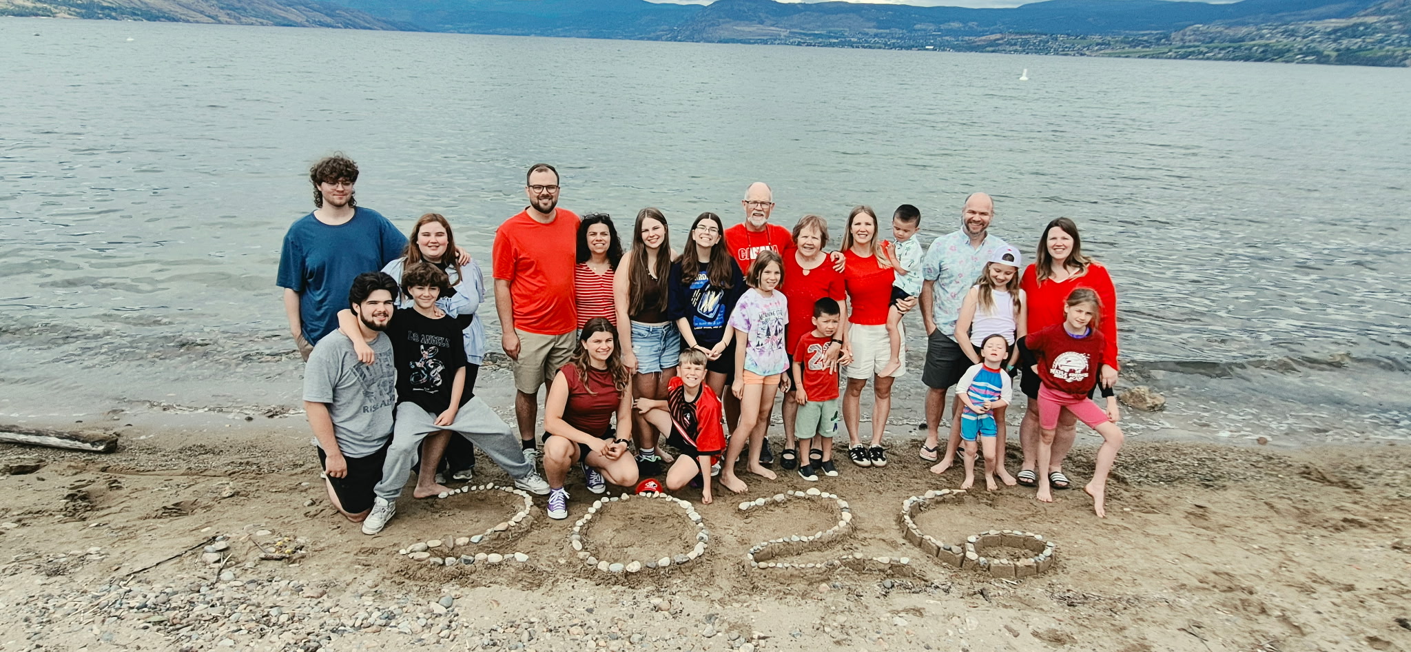Joyce and the Brinkerhoff family on the beach at Okanagan Lake, 2026 spelled out in stones